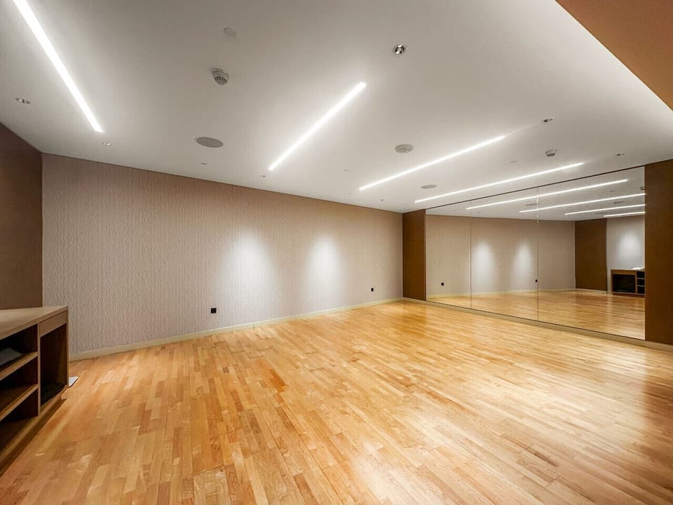 Spacious mirrored studio with wooden floors and modern ceiling lighting.