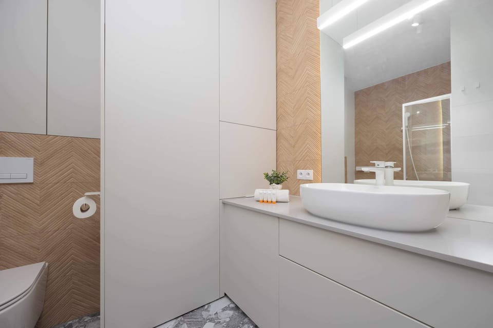 An elegant bathroom with a large mirror and bright finishes adds freshness and spaciousness to the interior.