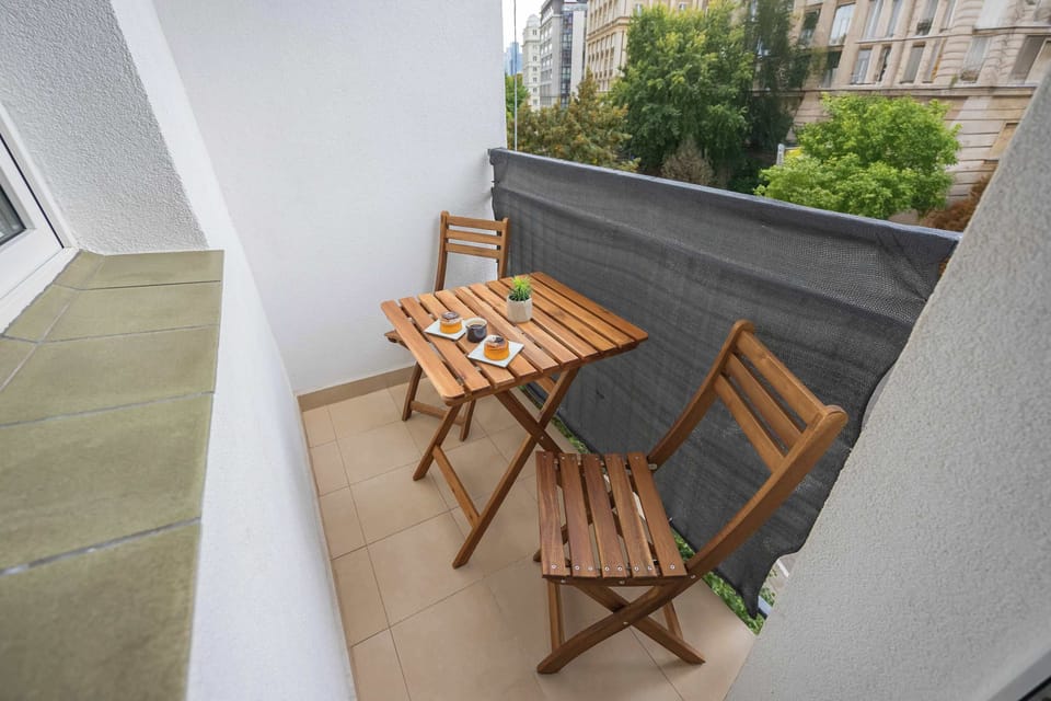 A balcony with a small table and two chairs, perfect for enjoying coffee or a view. The space is cozy and intimate.