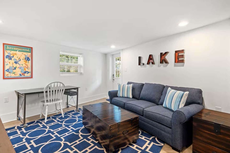 Another view of the living space featuring the bold navy rug, cozy seating, and a small desk by the window for remote work needs.