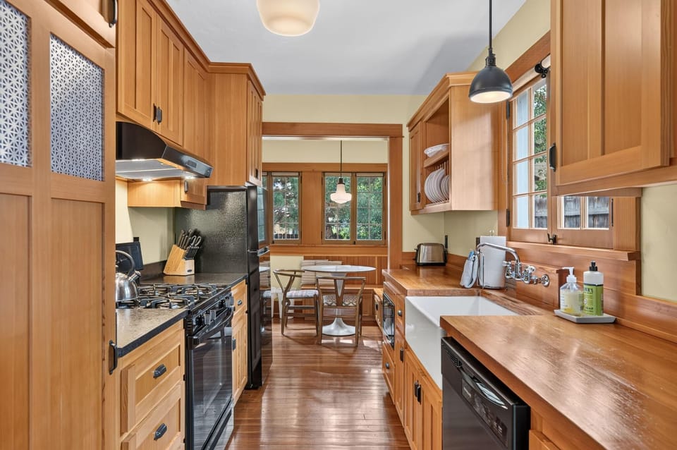 Fir cabinetry and butcher block counters line the galley kitchen with a farmhouse sink and modern appliances.