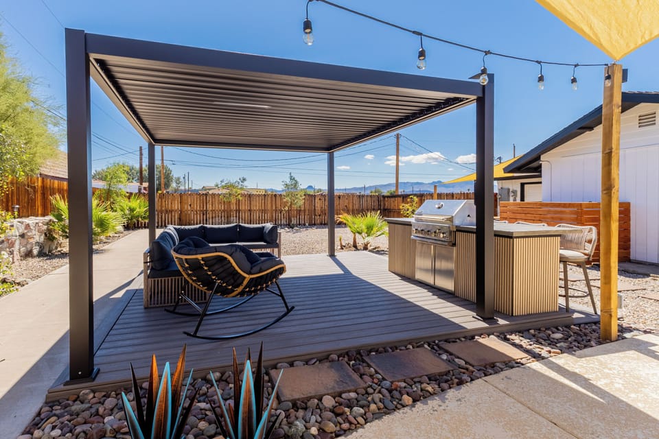 BBQ by the pool with cozy couches and bar seating for effortless outdoor fun.