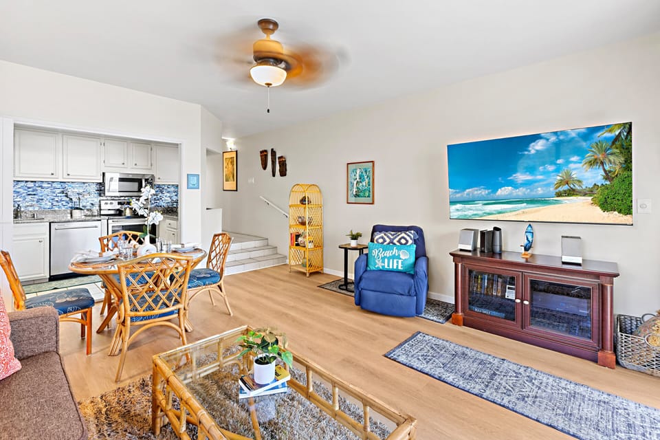 Relax in the spacious living area featuring a 65" Smart Roku TV, sofa sleeper, and dining table for four — ideal for entertaining or unwinding after a day on Maui's beaches.