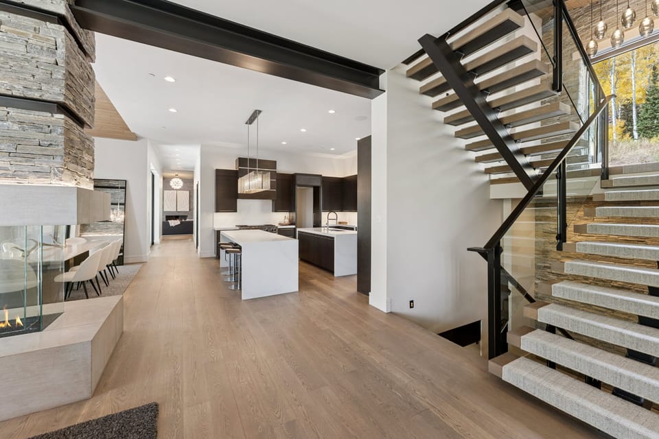 Open-concept kitchen and dining area with modern staircase and high ceilings
