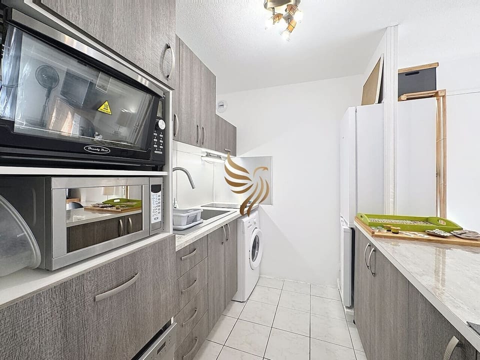 Cuisine moderne équipée avec four, micro-ondes, plaques de cuisson et rangements.