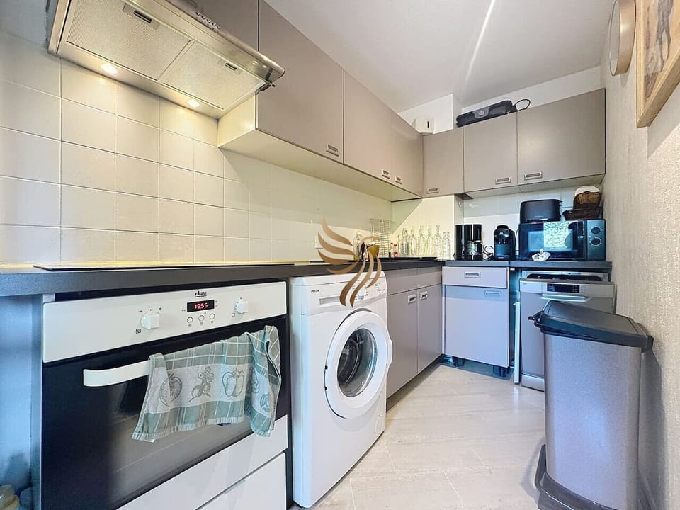Cuisine pratique et moderne comprenant lave-linge, lave-vaisselle, micro-ondes et petit électroménager.