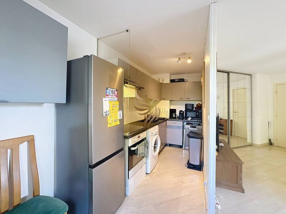 Cuisine équipée fonctionnelle avec réfrigérateur, four, plaque de cuisson et nombreux rangements.