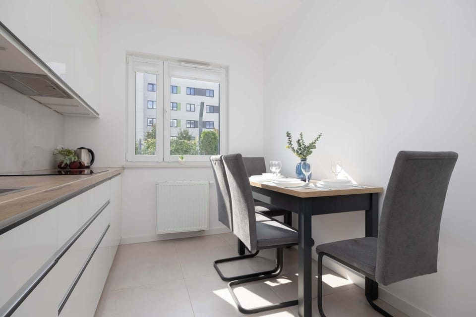 A dining area with a simple black table and gray chairs. A vase with flowers decorates the table, giving it a homely touch.