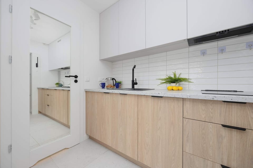 The white kitchen with wooden fronts and a large mirror above the countertop adds elegance and a sense of spaciousness to the interior.