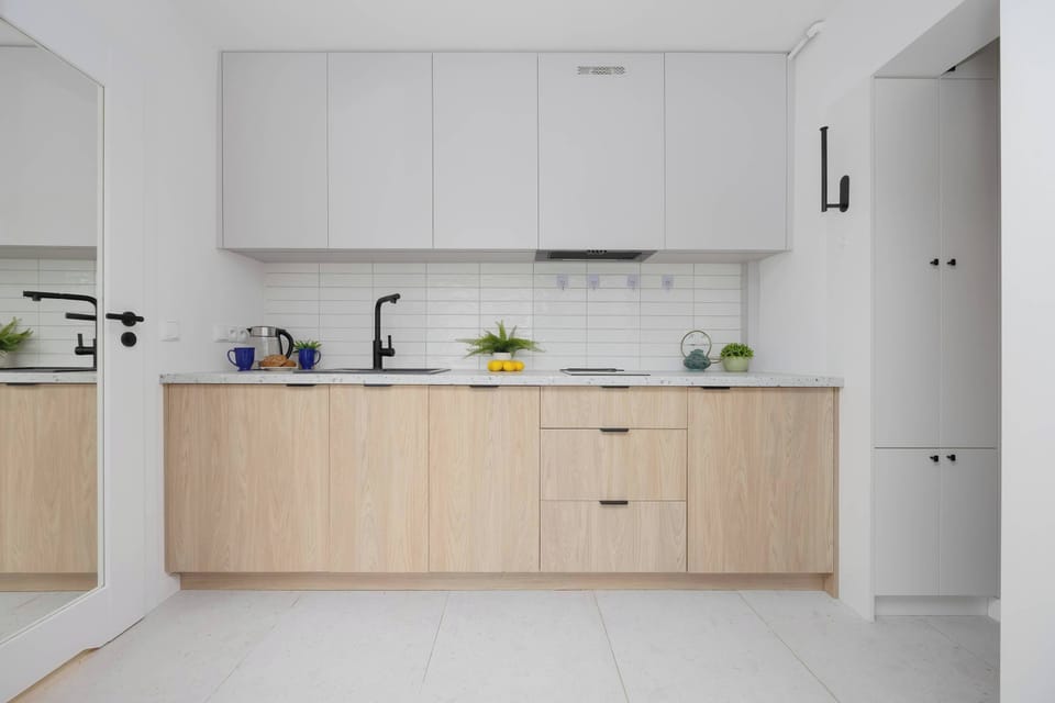 The modern kitchenette in bright tones is equipped with practical cabinets and a spacious countertop, making everyday cooking easier.