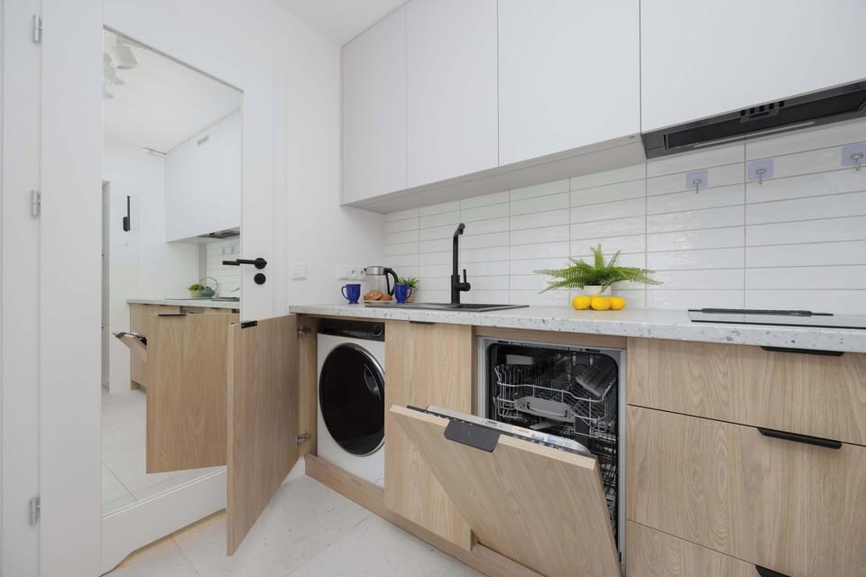 The kitchenette is equipped with modern appliances, including a dishwasher and a washing machine, enhancing the convenience of everyday stays.