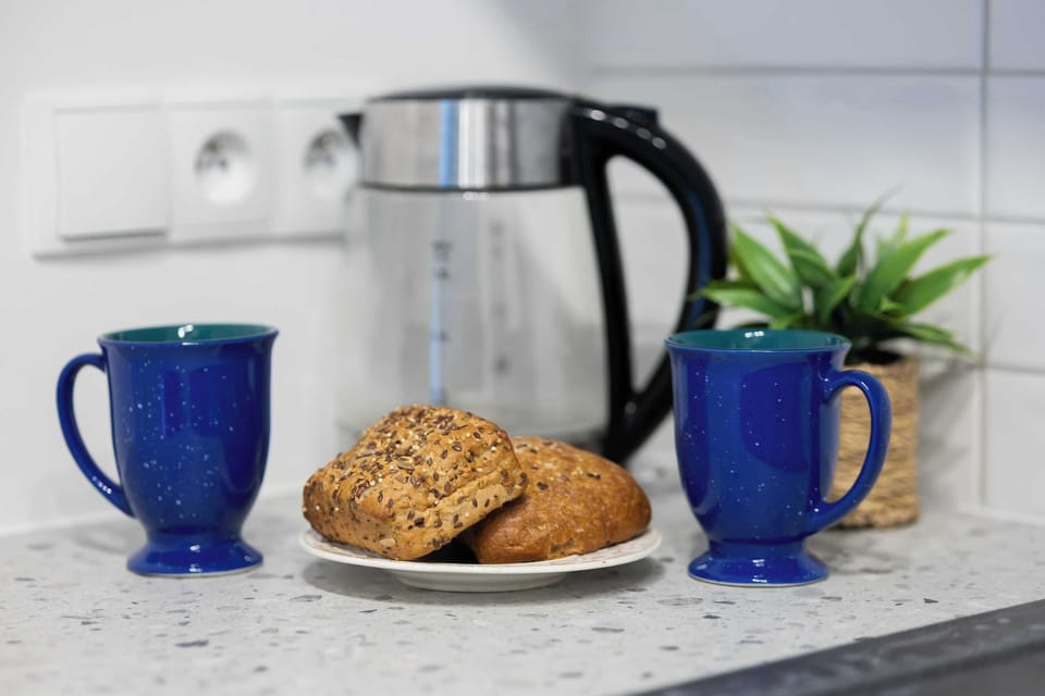 The kitchen counter decorated with mugs and fresh rolls invites you to start the day with aromatic coffee and breakfast in the comfort of home.