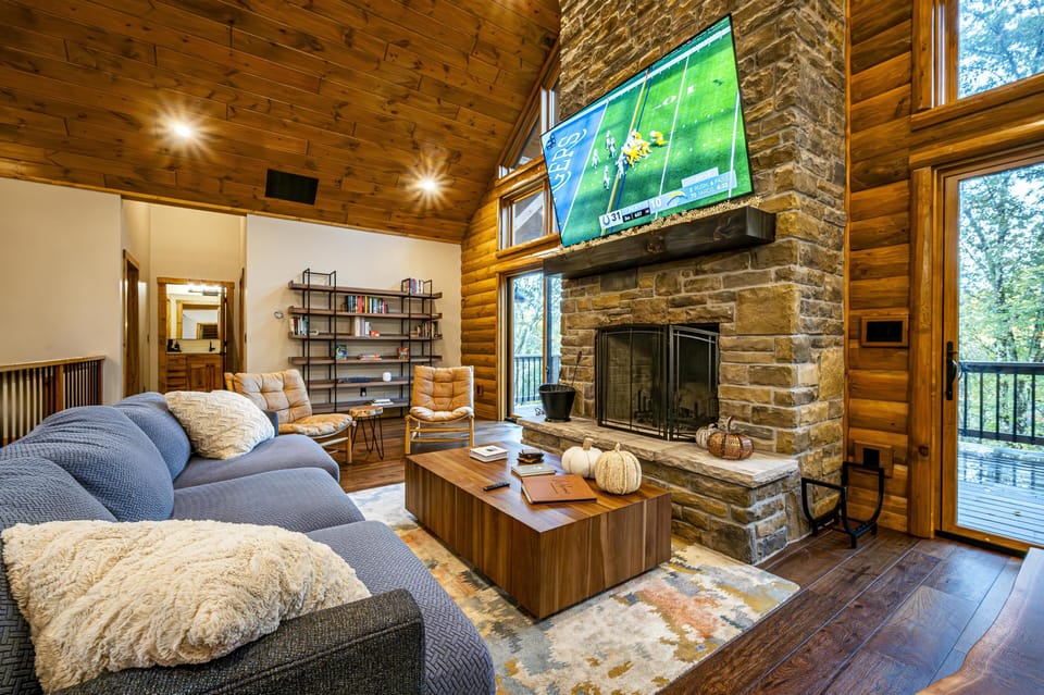 Cozy living room with stone fireplace and forest views