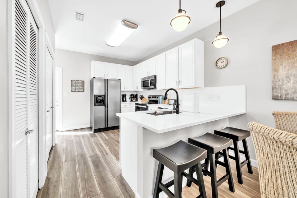 Your modern kitchen awaits with sleek white cabinets, stainless steel appliances, and a spacious island perfect for morning coffee or evening meals.
