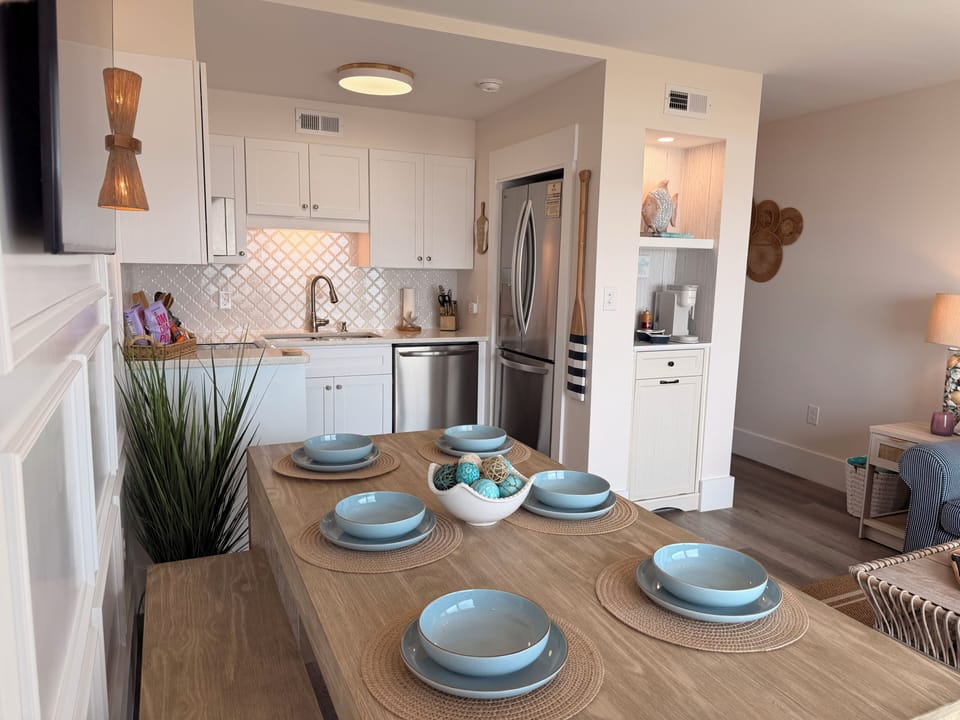 Bright coastal kitchen with stainless appliances and 6-seat dining table