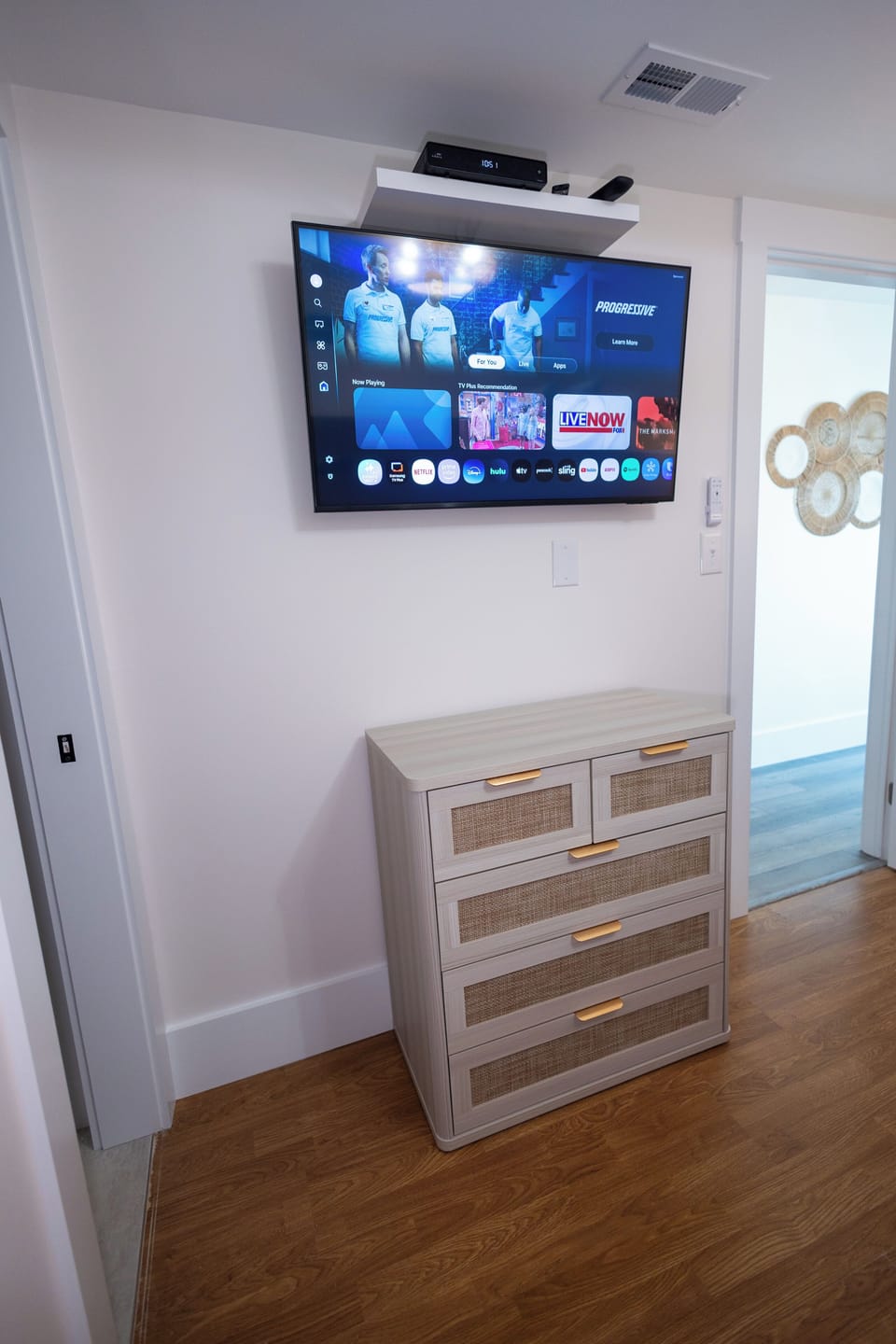 Second bedroom with smart TV and rattan dresser—stream and unwind