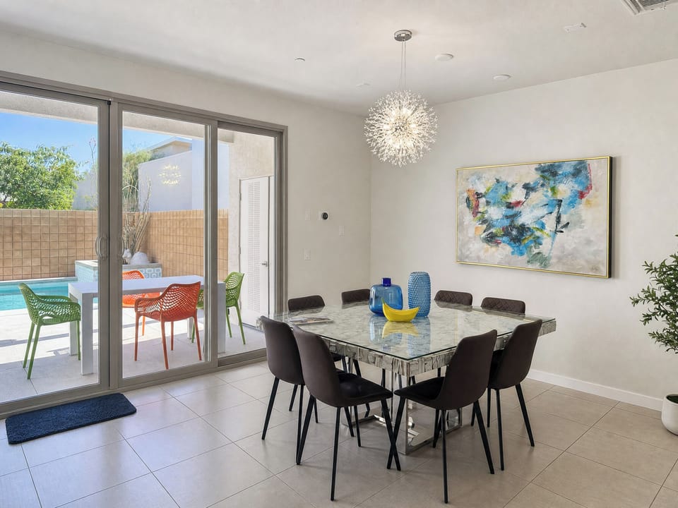Gather around this elegant dining table beneath the stunning starburst chandelier. Glass doors open to your private patio and sparkling pool, blending indoor comfort with outdoor leisure.