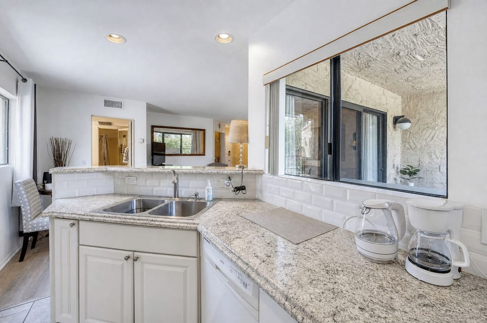 Bright, spacious kitchen with gleaming granite counters and crisp white cabinetry invites you to prepare your favorite meals while natural light pours in from every angle.
