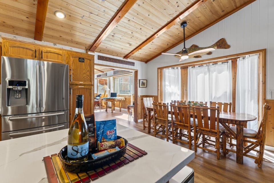 Warm dining area w/ long wood table & open flow into the fully equipped kitchen.