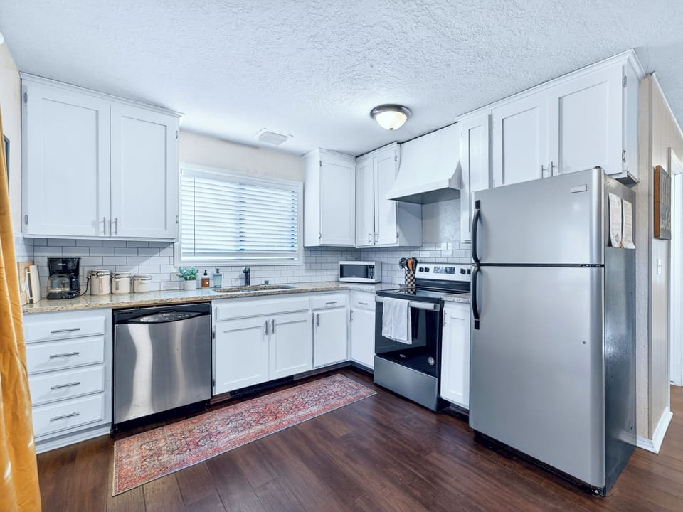 Bright kitchen with stainless appliances, subway tile, and coffee bar.