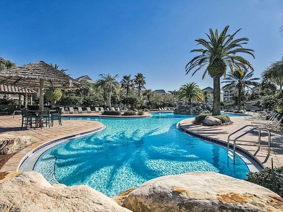 The Villages of Crystal Beach resort lagoon pool — just a 1–2 minute walk from your front door. Seasonally heated with loungers, palm trees, and a community hot tub.