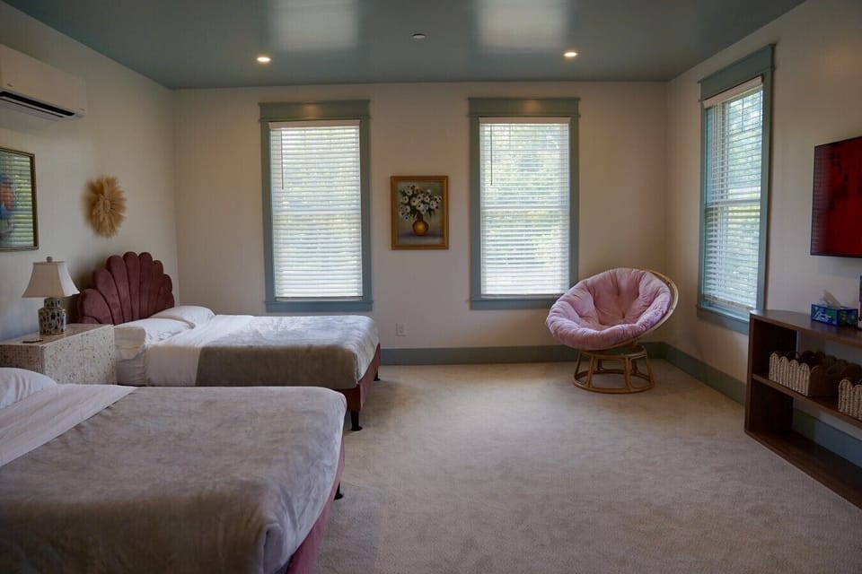 Another look at our spacious family room at Parkway House Goshen. Two full size beds with velvet scalloped headboards, a cozy papasan chair, wall mounted TV, and its own mini split for climate control give everyone room to spread out.