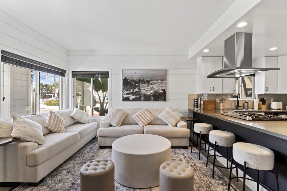 Open living & kitchen area w/ cozy sofa seating, island bar stools & bright windows filling the space w/ light