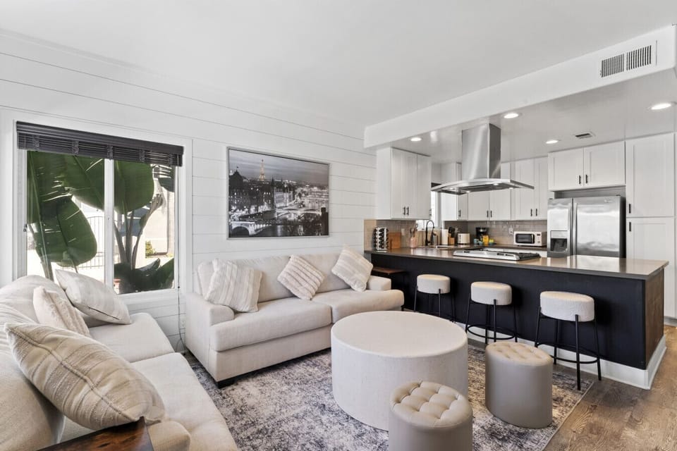 Stylish living area flowing into the kitchen, w/ soft seating & bar stools for casual hangouts