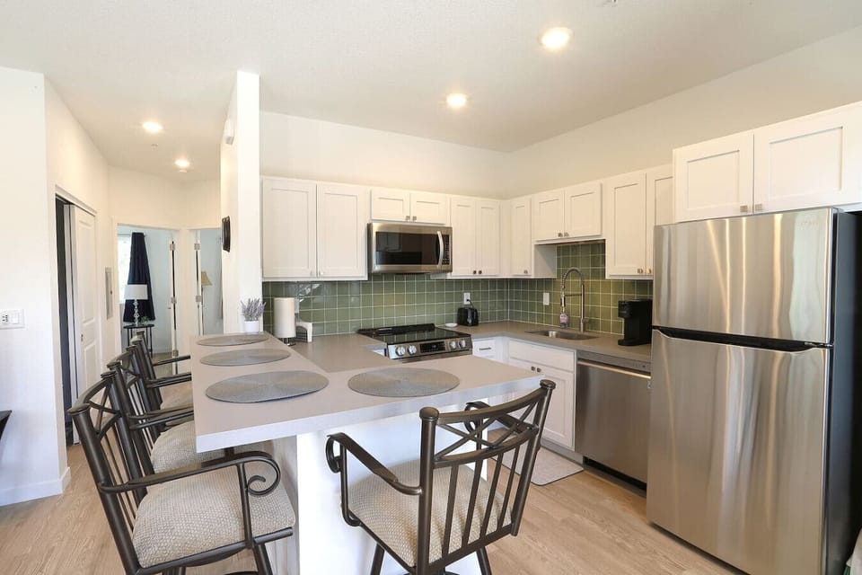 Modern kitchen fully equipped with stainless steel appliances and a spacious breakfast bar for casual dining.