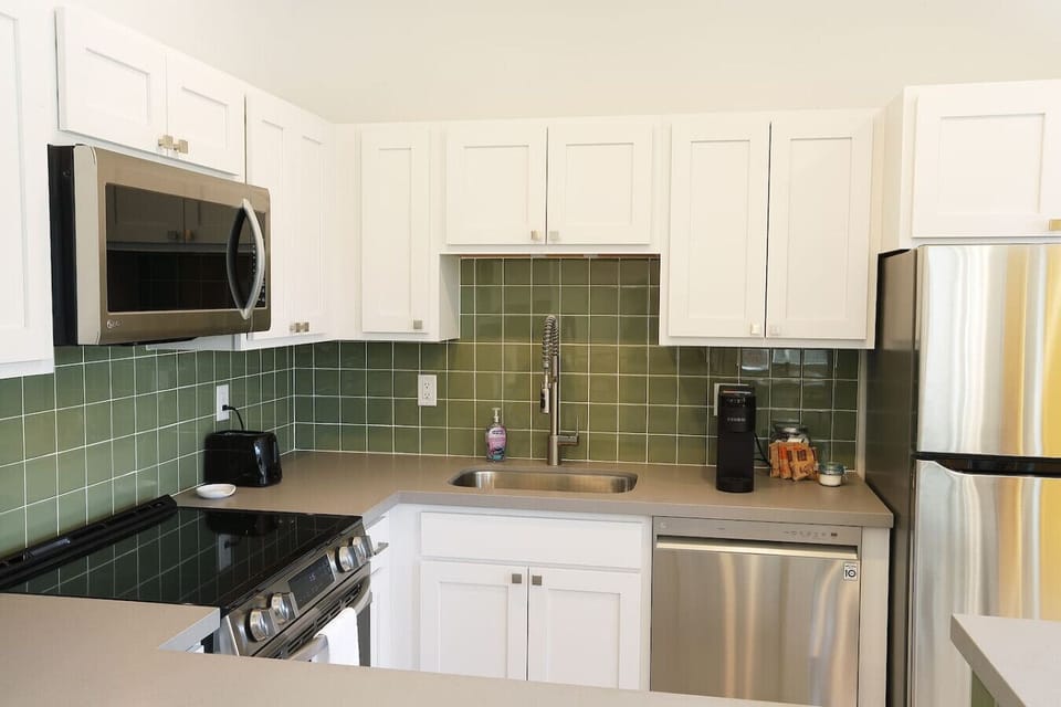 Fully equipped kitchen featuring stainless steel appliances - microwave, full-size refrigerator, dishwasher, modern stove with oven, and a high-arc pull-down faucet. Perfect for cooking meals or enjoying morning coffee together.