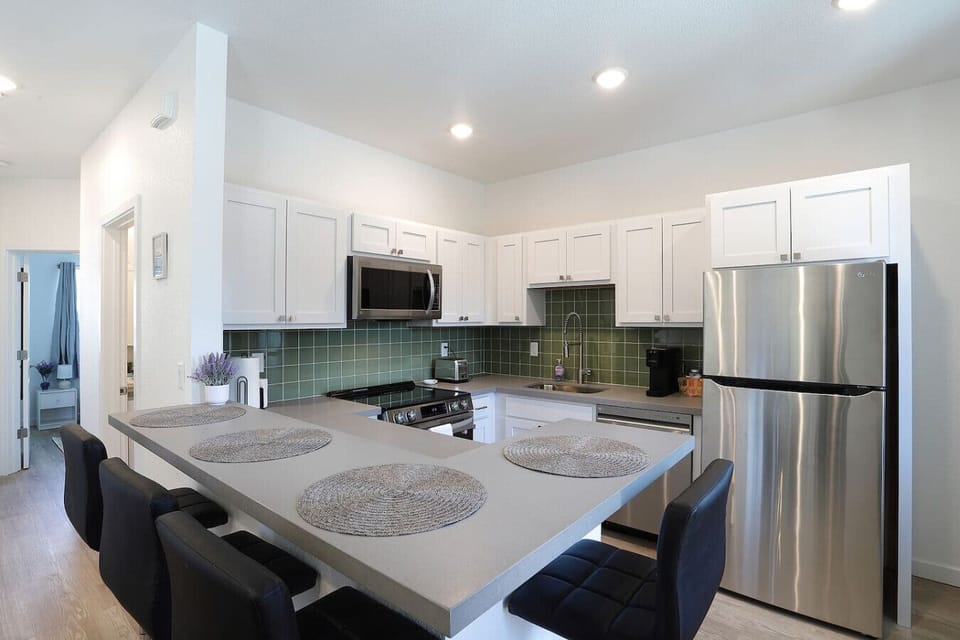 Modern kitchen fully equipped with stainless steel appliances and a spacious breakfast bar for casual dining.
