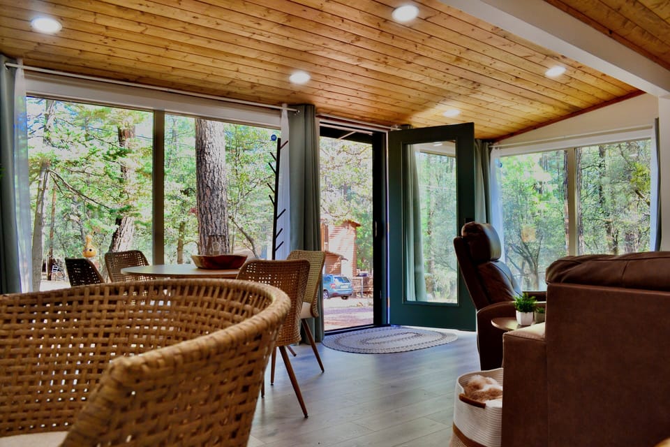 Open living and dining space with large forest-view windows