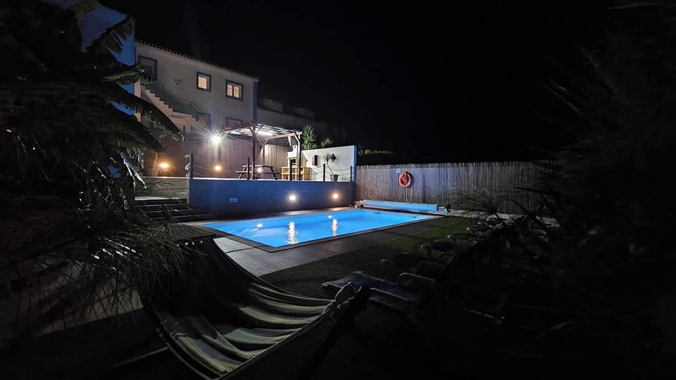 Piscina iluminada à noite, ambiente tranquilo e acolhedor.