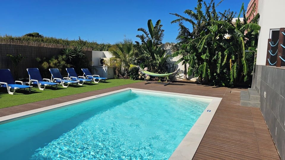 “Piscina , espreguiçadeiras e jardim tropical.