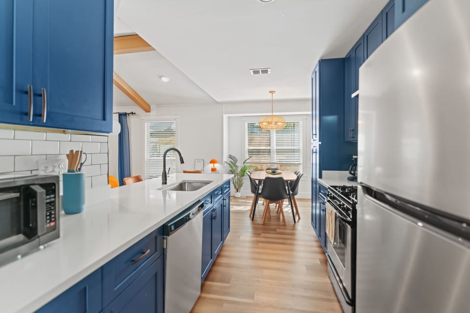 Open-concept kitchen and dining area with bold blue cabinetry and warm natural light—perfect for shared meals or morning coffee before exploring Austin.