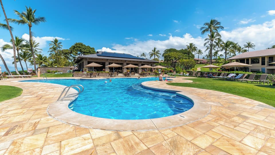The oceanfront resort pool features crystal-clear waters, tropical palms, and a newly renovated covered pavilion and fully equipped outdoor kitchen.