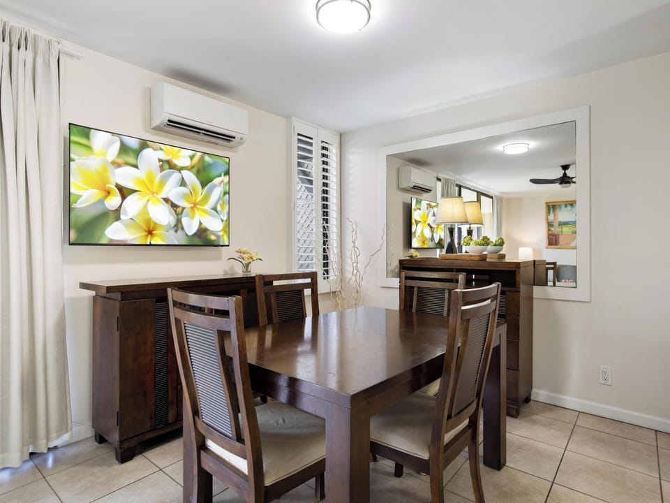 A welcoming dining space awaits your family meals, featuring warm wood furnishings and comfortable seating. The air-conditioned room flows seamlessly into the living area, creating a perfect gathering spot for your vacation.
