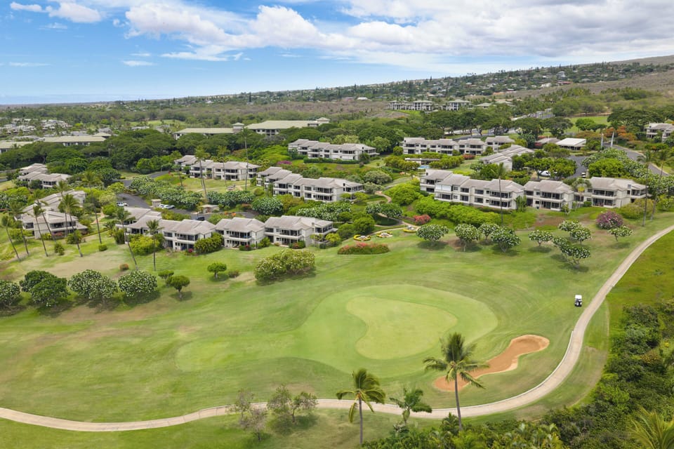 This aerial view showcases the property's location within a lush golf course community, surrounded by tropical landscaping and resort-style residences.
