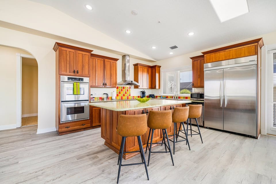 Kitchen from alternate angle showing dual stainless refrigerators, cabinetry, and island seating