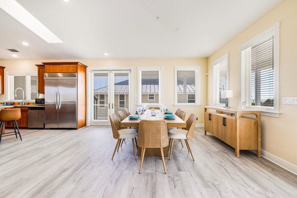 Open-concept kitchen and dining area with stainless steel refrigerator, island, and dining table with chairs