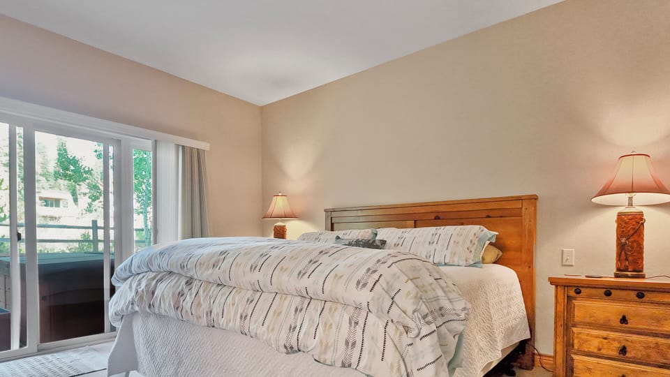 Bright bedroom with large window and soft bedding.