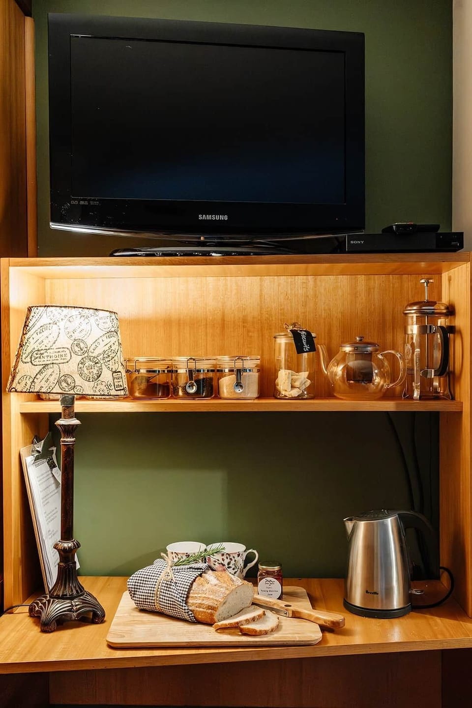Shelf with containers of teas, coffee, biscuits, teapot and French Press coffee maker 