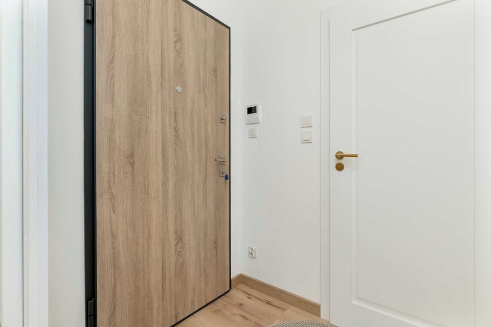 Bright hallway with white doors, wooden accents, and a clean minimalist aesthetic.