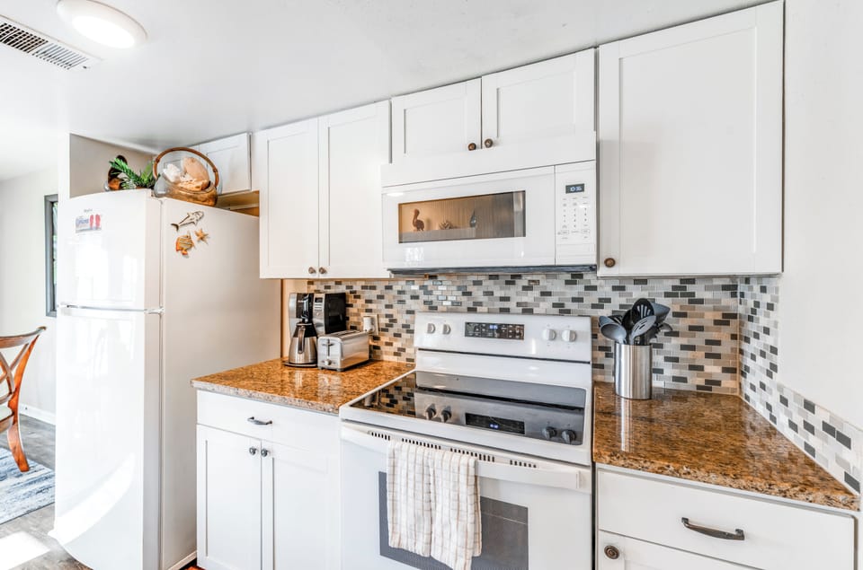 Your fully equipped kitchen features granite countertops, white cabinets, and modern appliances to create memorable meals during your stay.
