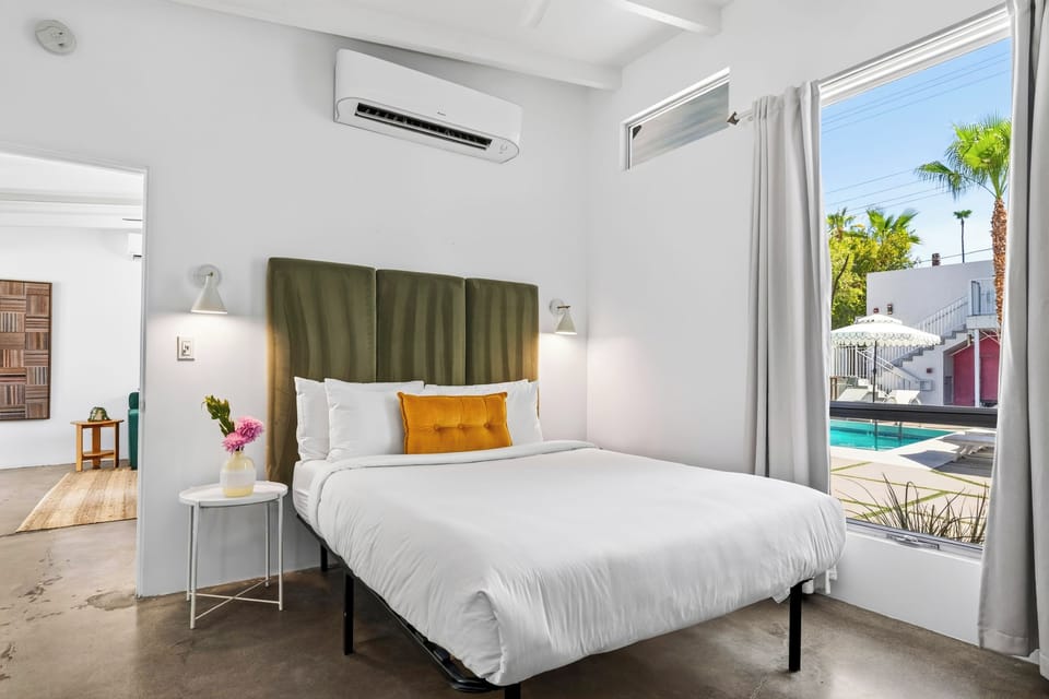 A king bed anchors this bright retreat, with oversized windows framing views of the pool courtyard just outside.