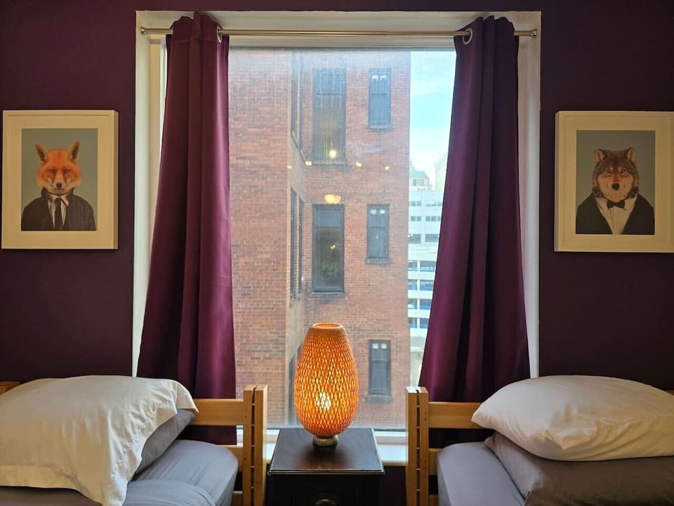 Twin beds beside oversized windows bringing in natural light and downtown city views.