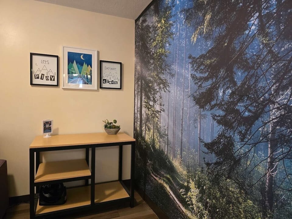 Convenient entry table and storage space beside a calming forest mural, perfect for luggage, personal items, or daily essentials