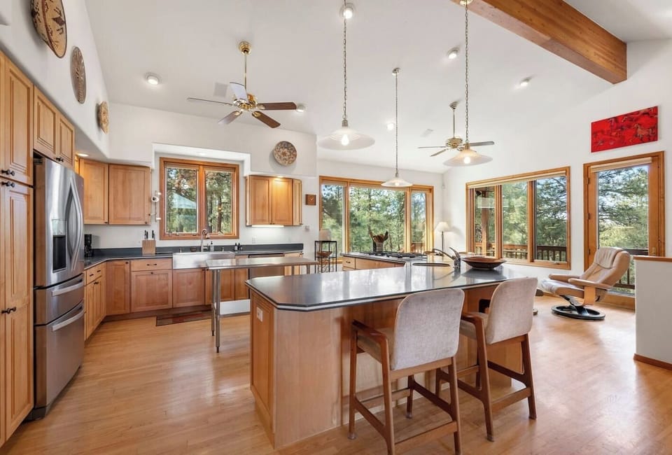 Bright and open kitchen with soaring ceilings, generous counter space, and multiple seating areas — the heart of the home where everyone naturally gathers to cook, connect, and share great food.