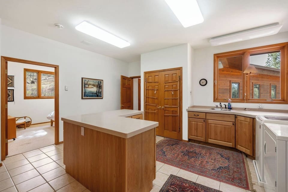 Large laundry room with washer, dryer, folding space, and a central island — convenient for longer stays, families, or refreshing gear after a day of outdoor adventures.