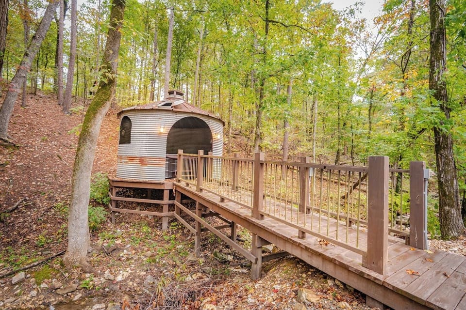 A rustic outdoor game area featuring a handcrafted cornhole board, perfect for family fun and entertainment. Enjoy quality time under the covered patio with barstools and seating overlooking the wooded surroundings.